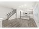 Bright, open-concept living space with gray wood floors and a staircase, adjacent to the kitchen at 537 Steinbeck Pl, Carmel, IN 46032