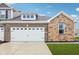 Two-car garage on a charming home exterior featuring brick and stone accents, plus manicured front lawn at 6433 Wasco Dr, Whitestown, IN 46075