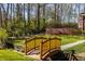 Charming backyard featuring a wooden bridge, manicured lawn, brick wall, and lush landscaping, creating a serene outdoor retreat at 7341 Washington Blvd, Indianapolis, IN 46240
