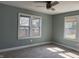 Bedroom with neutral carpet, a ceiling fan, and sun-filled windows with view of fenced yard at 2029 W 60Th St, Indianapolis, IN 46228