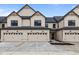 Modern townhome featuring light beige siding, black trim, and individual garages at 4195 Douro Trl, Westfield, IN 46062