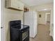 This kitchen features white cabinets, a black stove, a white refrigerator, and an adjacent doorway leading to another room at 4632 Normal Ave, Indianapolis, IN 46226