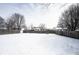 Snowy backyard surrounded by leafless trees and a wooden fence at 12643 Feldspar Rd, Indianapolis, IN 46236