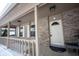 Close-up of the charming front porch with a swing, brick columns, and detailed front door and winter ground at 12643 Feldspar Rd, Indianapolis, IN 46236
