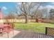 Backyard with deck, red table set, and large tree at 6149 Winnpeny Ln, Indianapolis, IN 46220