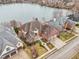 Aerial view of a beautiful brick home with a well-manicured front lawn and large driveway near the lake at 6437 N Oxbow Way, Indianapolis, IN 46220