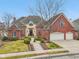 Charming brick exterior home with a two-car garage, complemented by a landscaped front yard and mature trees at 6437 N Oxbow Way, Indianapolis, IN 46220