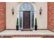Close up of a dark wooden front door with decorative glass sidelights and sconces for added curb appeal at 6437 N Oxbow Way, Indianapolis, IN 46220