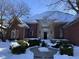 Charming brick home featuring arched windows, stucco accents and a snow-covered roof and landscaping at 6437 N Oxbow Way, Indianapolis, IN 46220