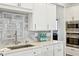 Close-up of the kitchen with stainless appliances, white cabinets, tiled backsplash, and a sink at 6437 N Oxbow Way, Indianapolis, IN 46220