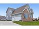 Exterior elevation showcases a three-car garage, brick accents, and manicured landscaping at 6777 Pulaski Ct, Carmel, IN 46033