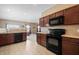 Modern kitchen with dark wood cabinets, black appliances, and tile floors at 7710 Silver Moon Way, Indianapolis, IN 46259