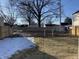 Fenced backyard with grass, snow, and mature trees at 2426 S Holt S Rd, Indianapolis, IN 46241