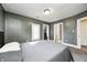 Spacious gray bedroom with a queen-size bed, large window, neutral carpeting, and access to both a closet and a full bathroom at 3356 N Park Ave, Indianapolis, IN 46205