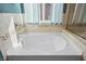 Close up on bright white soaking tub, tiled wall with window overlooking the backyard at 377 Morningside Dr, Brownsburg, IN 46112