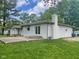 Rear view of the white brick house with a patio, deck, chimney, and large lawn at 5324 Mann Rd, Indianapolis, IN 46221