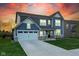 Charming two-story home with a well-manicured lawn and attached two-car garage with an evening sky overhead at 9812 Ridgecrest Ln, McCordsville, IN 46055