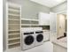 Well-organized laundry room equipped with modern washer, dryer, storage shelves and sink at 11710 Cold Creek Ct, Zionsville, IN 46077