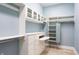 Custom walk-in closet with white shelving, drawers, glass cabinets, and pull-out ironing board at 11710 Cold Creek Ct, Zionsville, IN 46077