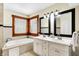 Bathroom featuring double vanity, soaking tub by window, neutral tile, and framed mirrors offer a serene and functional space at 1307 W 161St St, Westfield, IN 46074