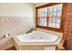 Comfortable soaking tub with jets and a window with blinds with a wood frame allowing sunlight to stream in at 1307 W 161St St, Westfield, IN 46074