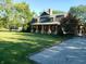 Lovely home with a covered porch, lush green lawn, mature trees, and a stone driveway, creating a picturesque setting at 1307 W 161St St, Westfield, IN 46074