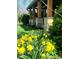 Close-up shot of a charming front porch, enhanced by yellow spring flowers, green bushes, and natural stone porch columns at 1307 W 161St St, Westfield, IN 46074