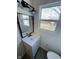 Bathroom with white vanity, modern faucet, wood framed mirror and a large window with natural light at 310 S Gerrard Dr, Indianapolis, IN 46241