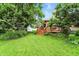 A verdant backyard features a lush lawn, mature trees, a wooden deck and storage shed at 4646 Rocky Knob Ln, Indianapolis, IN 46254
