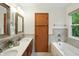 Bright bathroom with dual vanity sinks, modern lighting, wood cabinets, and a separate tub and shower at 4646 Rocky Knob Ln, Indianapolis, IN 46254