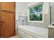 Bright bathroom featuring a shower-tub, a window with trees, and a towel rack mounted on the door at 4646 Rocky Knob Ln, Indianapolis, IN 46254