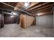 Unfinished basement featuring exposed ceiling beams, brick accent wall, and concrete flooring ready for customization at 8041 Halyard Way, Indianapolis, IN 46236