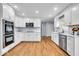 Bright kitchen featuring white cabinets, stainless steel appliances, hardwood floors, and modern countertops at 9031 Butternut Ct, Indianapolis, IN 46260