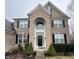 Close-up of the stately front entrance, showcasing the stone archway, black door, and decorative landscaping at 2504 Fawn Bluff Ct, Zionsville, IN 46077