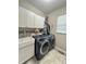 Well-equipped laundry room with modern washer and dryer, sink, cabinets, and stylish backsplash at 2504 Fawn Bluff Ct, Zionsville, IN 46077