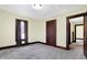 This bedroom features neutral carpet, tan walls, and dark stained trim around the floors and doors at 403 Colescott St, Shelbyville, IN 46176