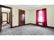Bedroom showing neutral walls and carpet, window with red drapes and original wood trim at 403 Colescott St, Shelbyville, IN 46176