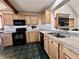 Well-lit kitchen with wood cabinets, black appliances, and open view to the living area at 1072 S State Road 67, Martinsville, IN 46151