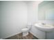 Half bathroom featuring a white toilet, laminate floors, and white pedestal sink with a mirror at 1407 Foxtail Ln, Greenwood, IN 46143