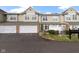 Two-story townhome featuring an attached garage, brick accents, and lush landscaping at 2231 Colfax Ln, Indianapolis, IN 46260