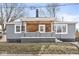 Charming home featuring gray siding, brick accents, and a cozy porch with wood paneling and wrought iron details at 2421 E 11Th St, Indianapolis, IN 46201