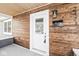 Close-up of the front porch featuring wood paneling, a white front door, and visible house numbers at 2421 E 11Th St, Indianapolis, IN 46201