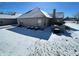 Exterior view of the backyard covered in snow with brick exterior and lush green landscaping at 5850 Bradston Way, Indianapolis, IN 46237