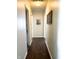 A hallway with wood floors and neutral walls featuring framed pictures and doorways at 5850 Bradston Way, Indianapolis, IN 46237