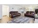Spacious living room with two brown leather reclining sofas and a view of the kitchen at 6354 River Run Dr, Indianapolis, IN 46221