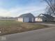 View of detached garage with gray siding, as well as the house, surrounded by a large lawn at 1510 Josephine St, Martinsville, IN 46151