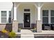 Inviting front porch showcasing gray brick pillars, black front door and comfortable seating area at 16012 Forewood Ln, Fishers, IN 46037