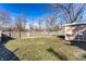 Large backyard with green grass, bordered by a wooden fence, and shaded by mature trees at 3144 Voigt Dr, Indianapolis, IN 46224