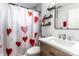 Bright bathroom featuring a modern vanity, decorative shelves, and a shower with a heart-themed curtain at 3144 Voigt Dr, Indianapolis, IN 46224