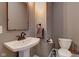 Small bathroom with pedestal sink, toilet, and dark mirror at 317 N Arsenal Ave, Indianapolis, IN 46201
